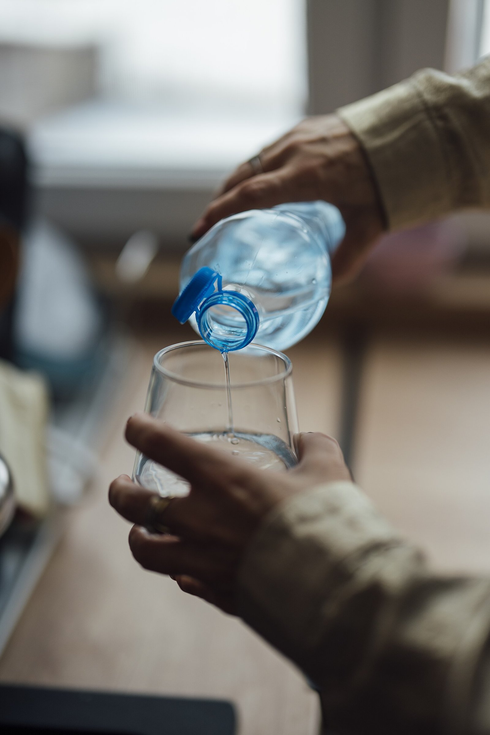 Hands pouring water into a glass illustrating fluid-first habits after lithotripsy
