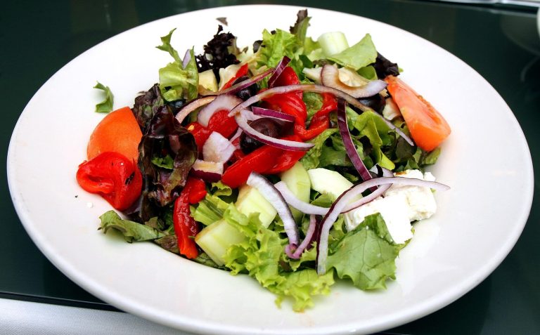 Plate of mixed green salad with tomatoes and onion, a high-volume food for a sleep apnea diet