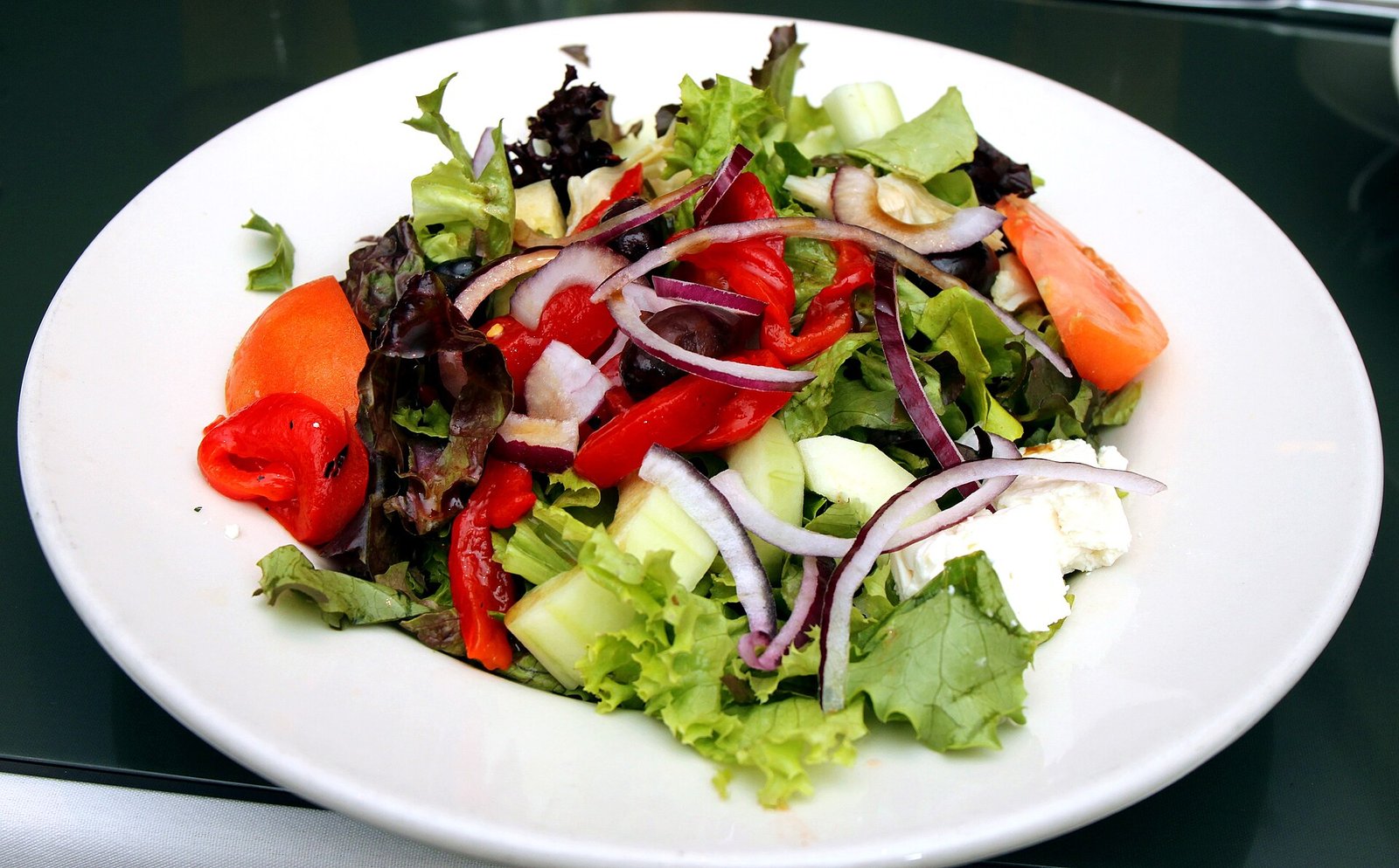 Plate of mixed green salad with tomatoes and onion, a high-volume food for a sleep apnea diet