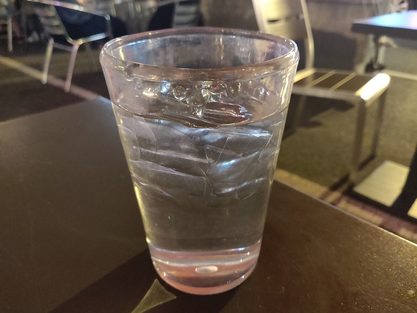 Glass of water at an outdoor table: hydration and regular meals are core migraine diet habits