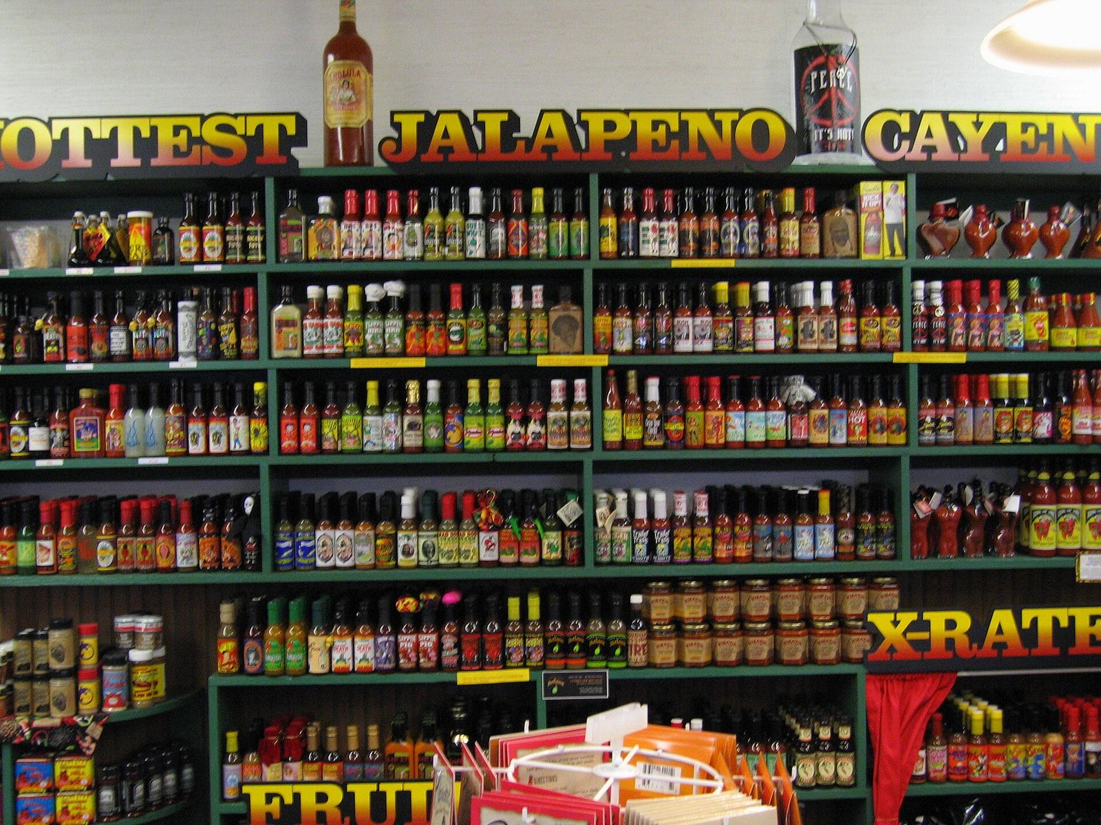 Shelves of hot sauce bottles; capsaicin-rich spicy foods are common rosacea diet triggers